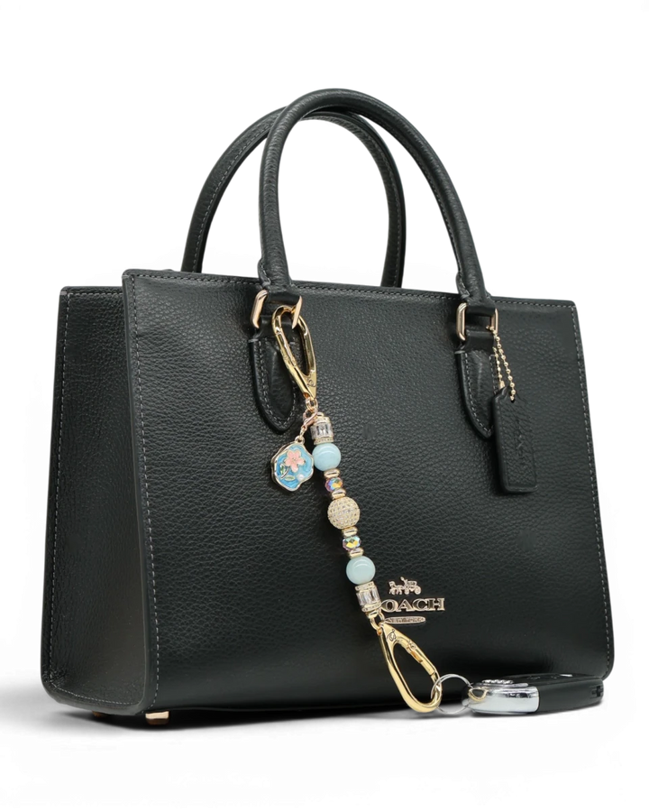 LD Keyfinder Petite Pastel Garden charm with aquamarine, pink glass beads, and gold-plated flower charm on a black handbag.