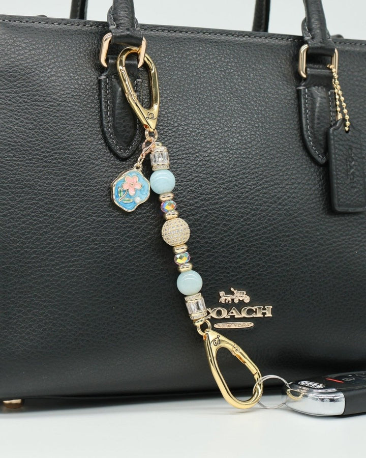 LD Keyfinder Petite Pastel Garden charm with aquamarine, pink glass beads, and gold-plated flower charm on a black handbag.