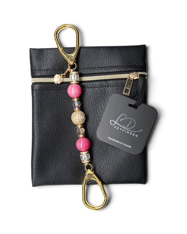 LD Keyfinder Petite Radiant Hope beaded keychain with pink jade, gold pavé, and ribbon charm on a black leather pouch.