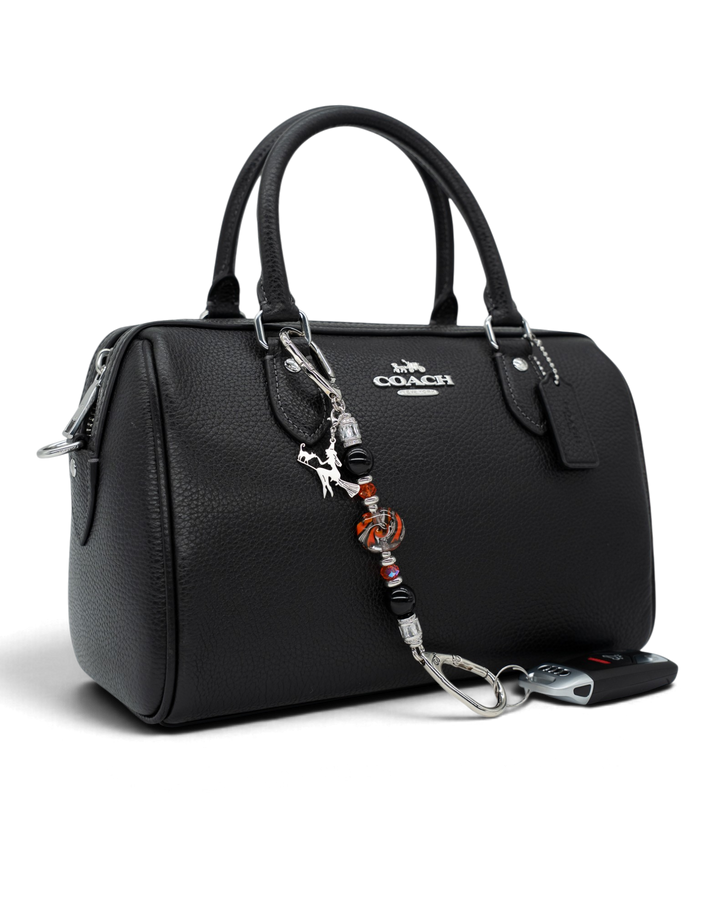 LD Keyfinder Petite Spellbound Halloween charm featuring obsidian, orange glass, and a witch on a broom on a black bag.