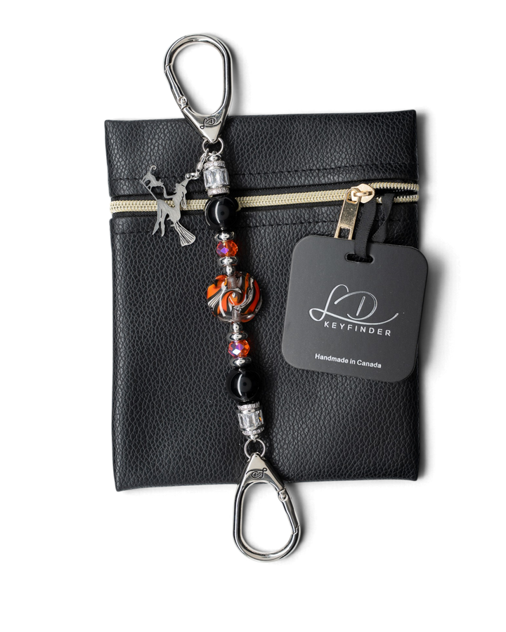 LD Keyfinder Petite Spellbound Halloween keychain with obsidian, orange glass, and a witch charm on a leather pouch.