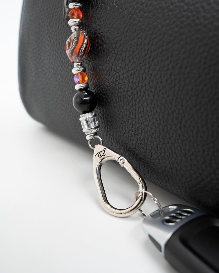 LD Keyfinder Petite Spellbound Halloween keychain with black obsidian, orange glass beads, and a witch charm on a bag.
