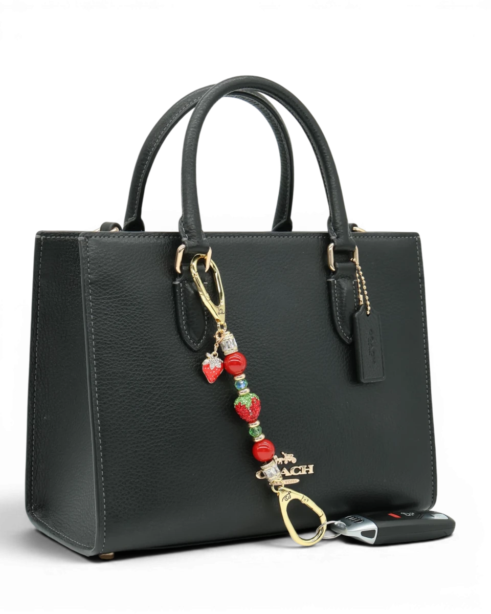 LD Keyfinder Petite Strawberry Fields charm with red pearls, green glass beads, and a crystal strawberry on a handbag.
