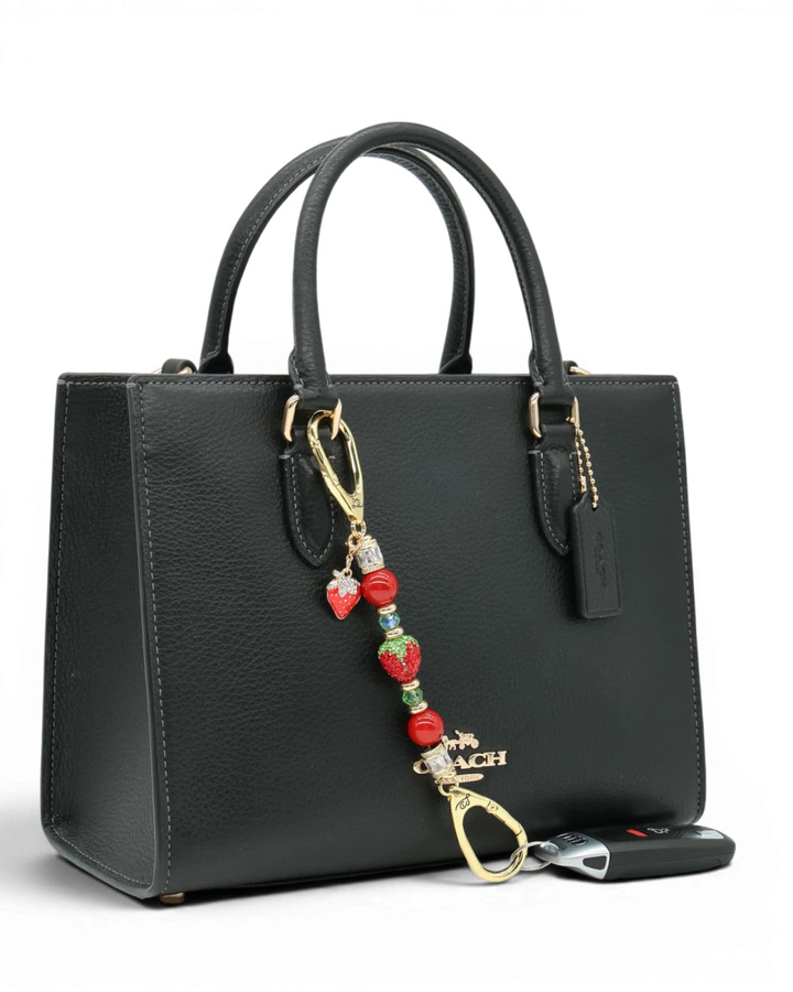 LD Keyfinder Petite Strawberry Fields charm with red pearls, green glass beads, and a crystal strawberry on a handbag.