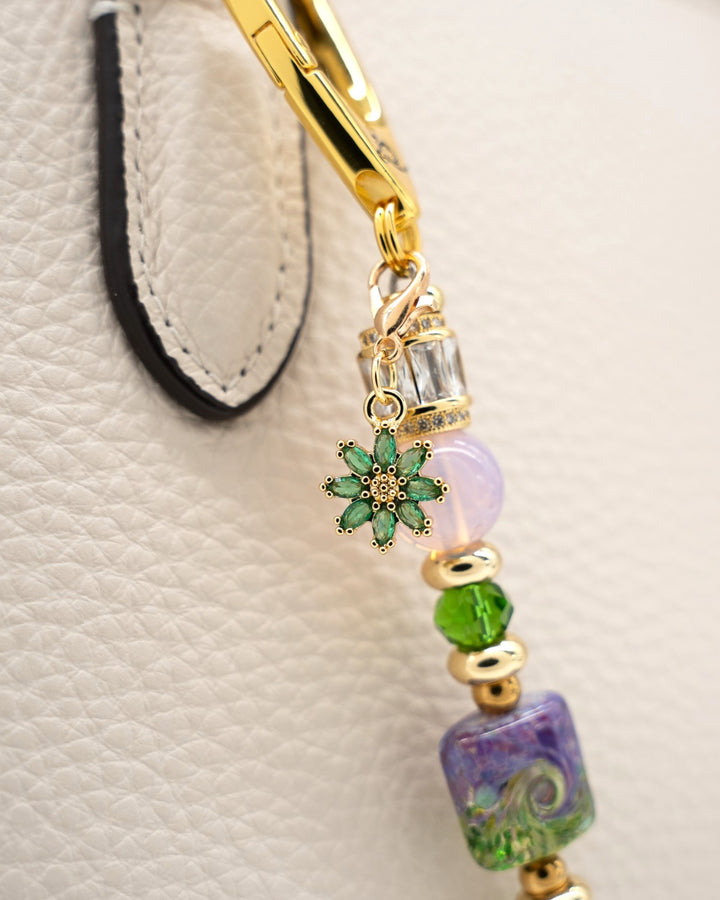 LD Keyfinder Petite Verdant Bloom accessory with lampwork glass, pink opalite, and gold flower charm on a handbag.
