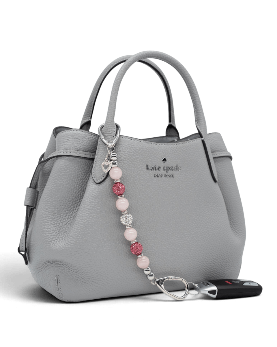 LD Keyfinder Princess Pink rose quartz beaded key fob with rhinestone heart charm attached to a grey leather handbag.