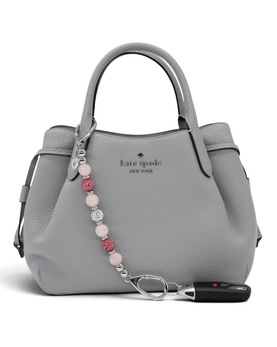 LD Keyfinder Princess Pink rose quartz beaded keychain with rhinestone heart charm attached to a grey leather handbag