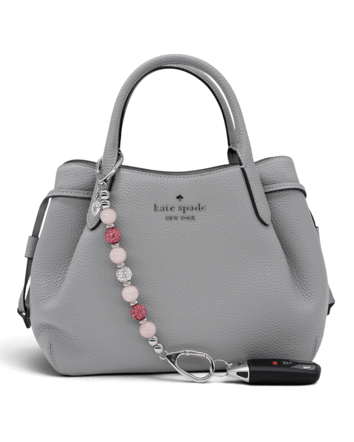 LD Keyfinder Princess Pink rose quartz beaded keychain with rhinestone heart charm attached to a grey leather handbag