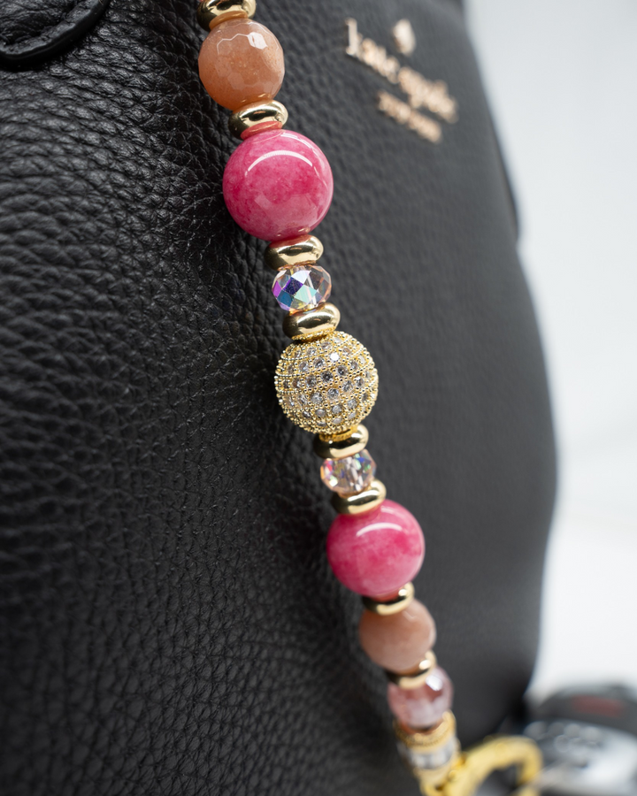 LD Keyfinder Radiant Hope beaded keychain with pink quartz, sunstone, and gold pavé charm on a black leather bag