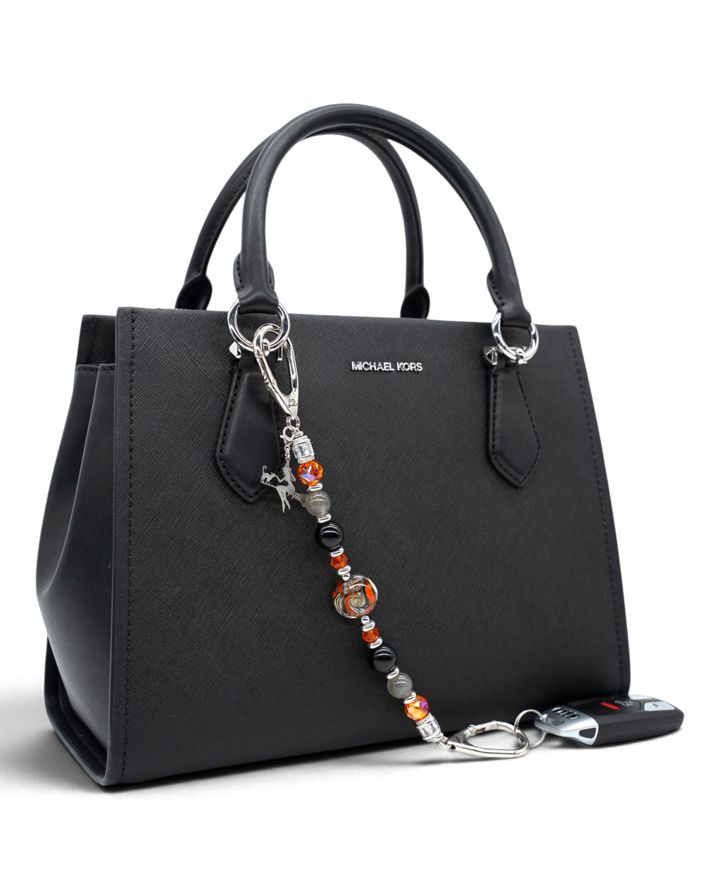 LD Keyfinder Spellbound accessory with obsidian, moonstone, and orange glass beads attached to a black handbag