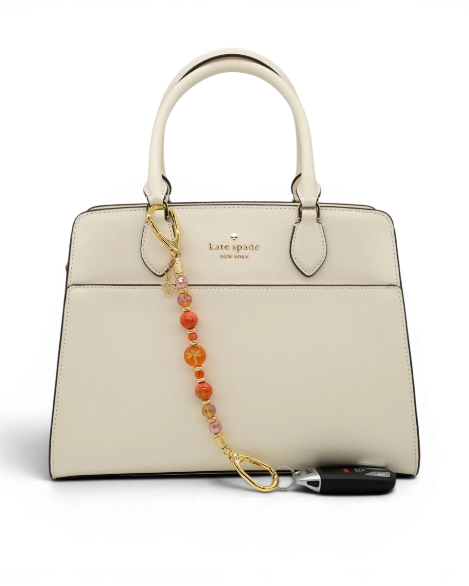 LD Keyfinder Summer Sunset beaded accessory with cherry quartz, agate, and dragonfly charm attached to a white handbag.