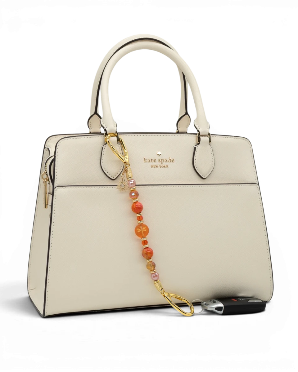 LD Keyfinder Summer Sunset beaded keychain with coral glass, cherry quartz, and gold sun charm attached to a cream bag