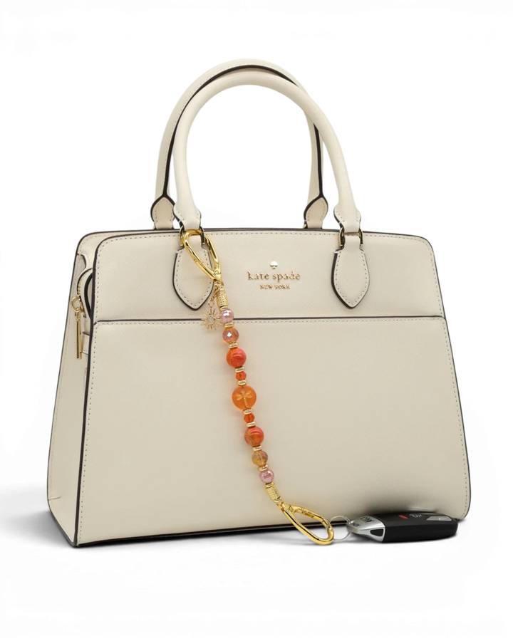 LD Keyfinder Summer Sunset beaded keychain with coral glass, cherry quartz, and gold sun charm attached to a cream bag