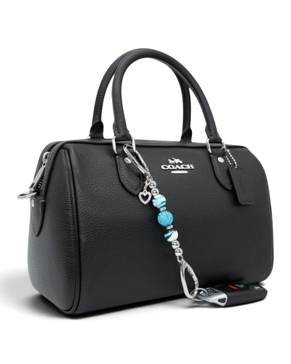 LD Keyfinder Teal My Heart-Mini charm with teal swirl glass beads and a silver heart attached to a black leather bag.