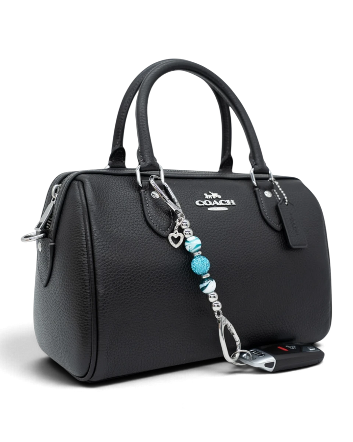 LD Keyfinder Teal My Heart-Mini charm with teal swirl glass beads and a silver heart attached to a black leather bag.