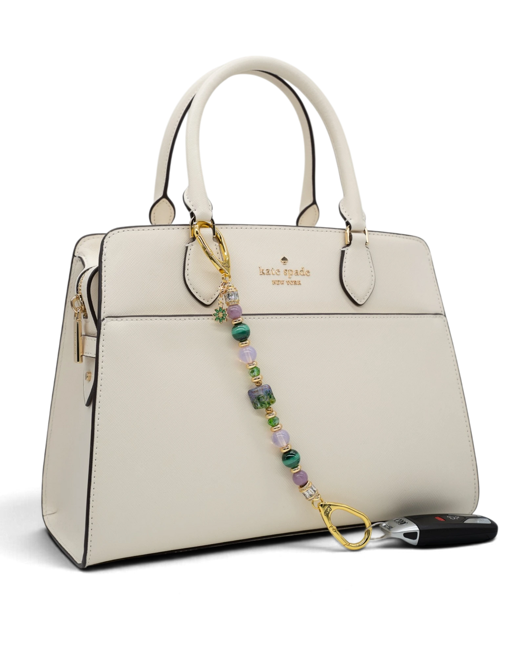 LD Keyfinder Verdant Bloom beaded keychain with malachite, opalite, and lampwork glass attached to a white handbag