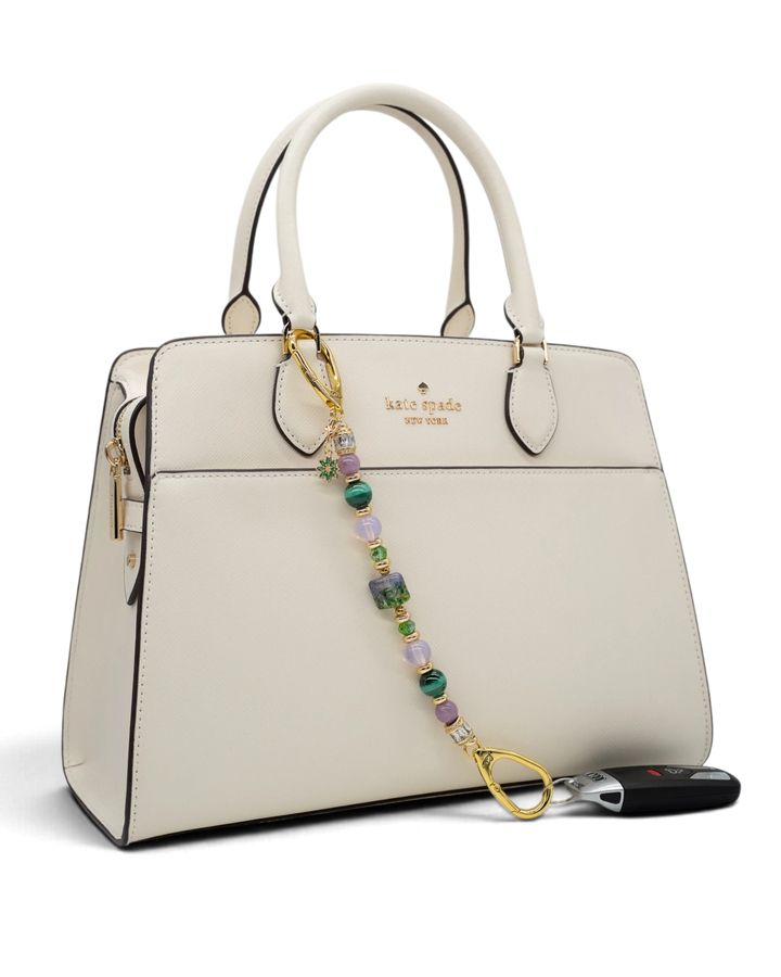 LD Keyfinder Verdant Bloom beaded keychain with malachite, opalite, and lampwork glass attached to a white handbag
