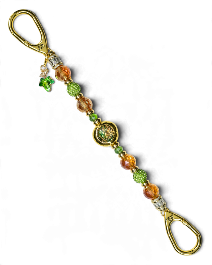 LD Keyfinder Verdant Flame accessory featuring green and burnt orange beads with a gold-plated leaf charm and centerpiece