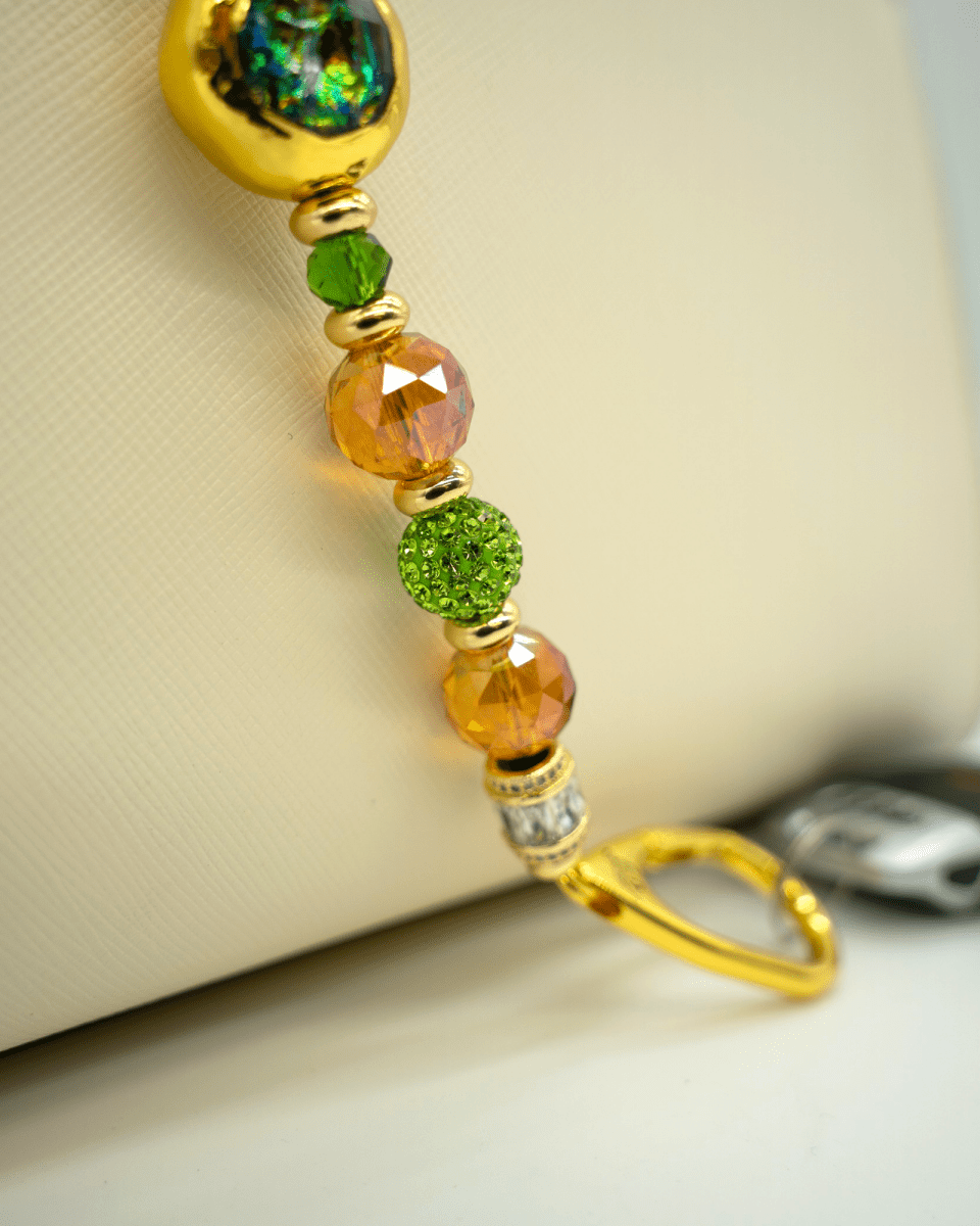 LD Keyfinder Verdant Flame featuring green and orange crystal beads, gold-plated spacers, and a resin centerpiece.