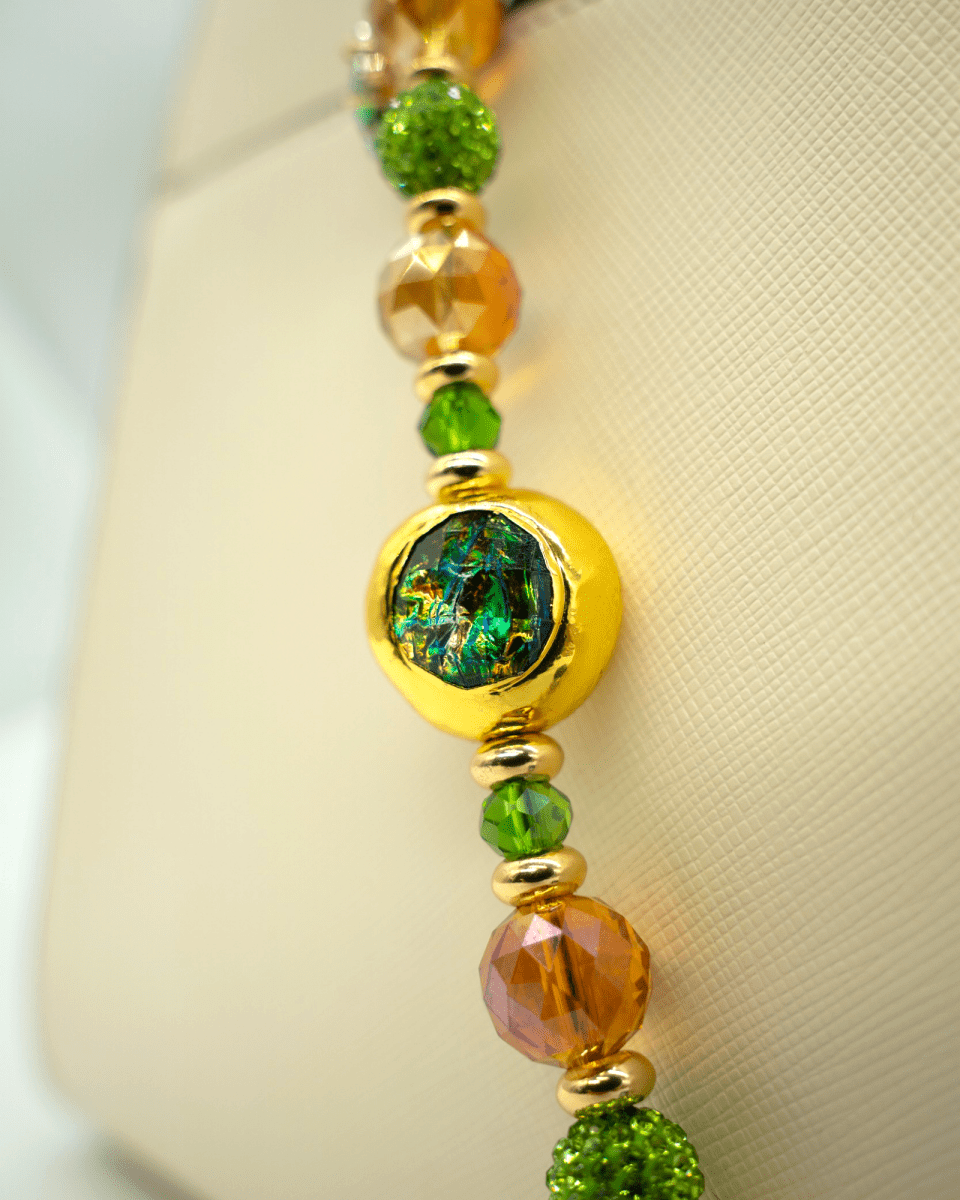 LD Keyfinder Verdant Flame beaded accessory featuring a gold-plated resin centerpiece, green crystals, and orange beads.