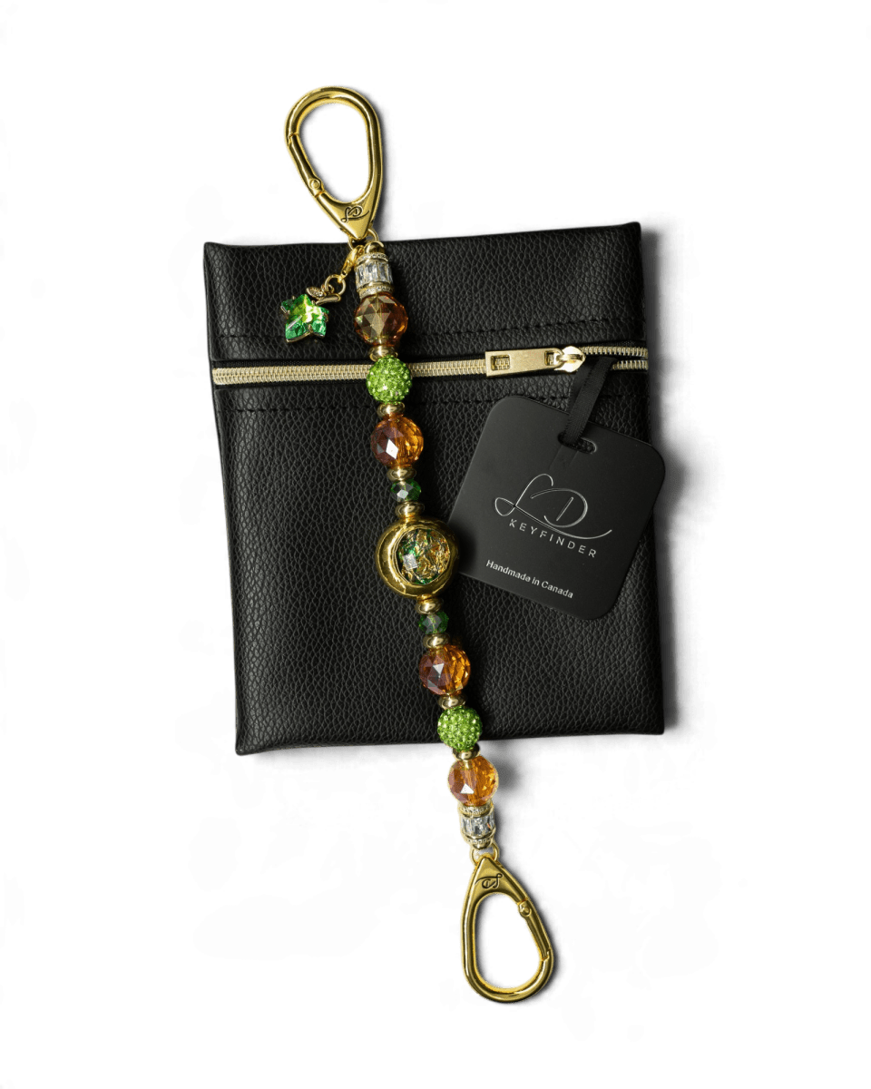 LD Keyfinder Verdant Flame beaded accessory with green and orange crystals, gold accents, and a leaf charm on a pouch.