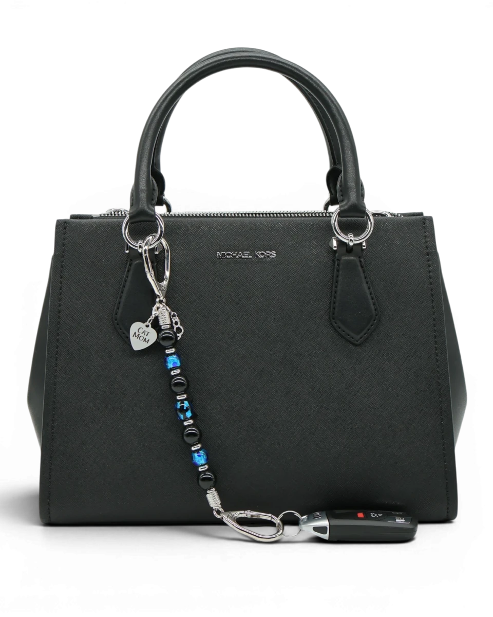 LD Keyfinder Whisker Dreams beaded keychain with black obsidian and blue foil glass beads attached to a black handbag.