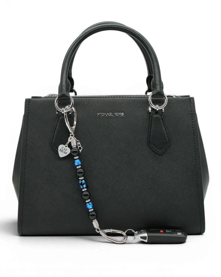 LD Keyfinder Whisker Dreams beaded keychain with black obsidian and blue foil glass beads attached to a black handbag.