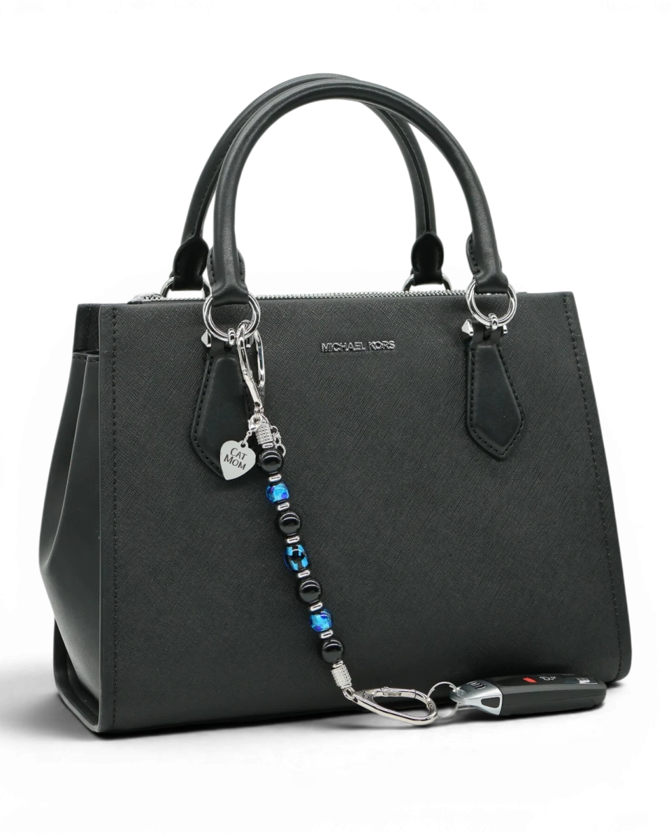 LD Keyfinder Whisker Dreams beaded keychain with black obsidian and blue foil glass beads attached to a black handbag.