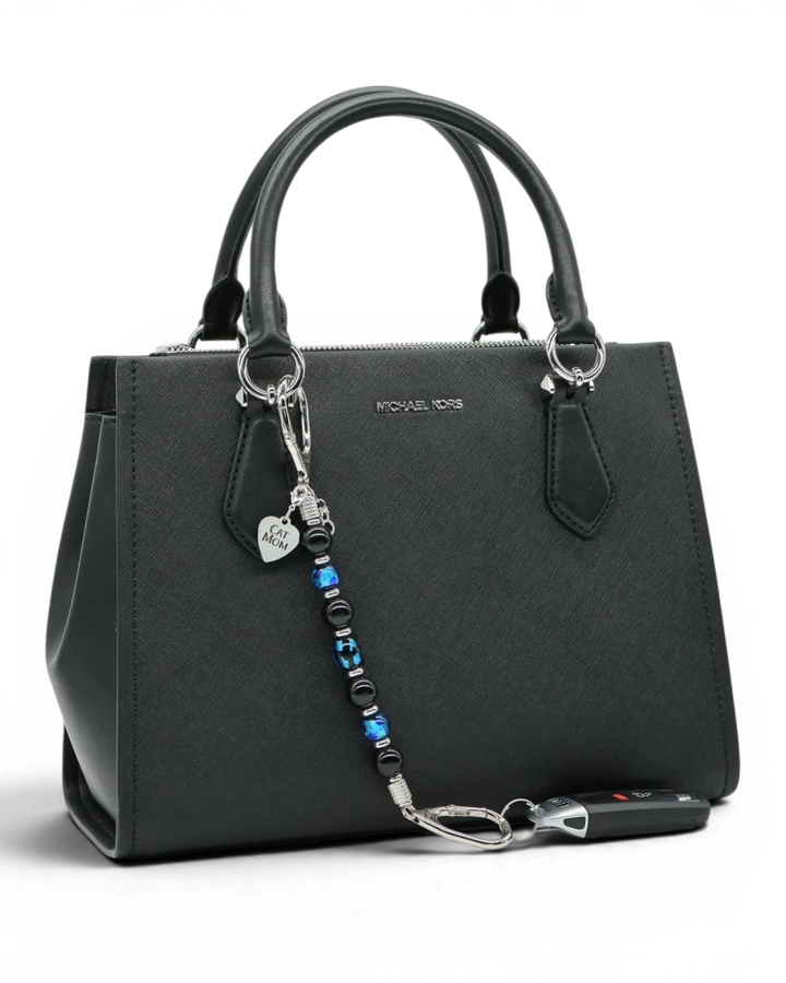 LD Keyfinder Whisker Dreams beaded keychain with black obsidian and blue foil glass beads attached to a black handbag.