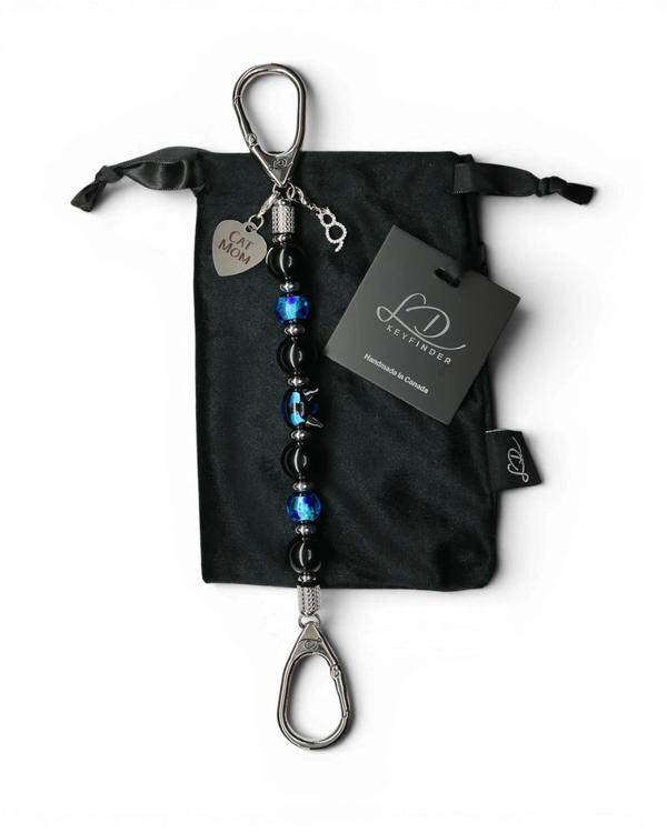 LD Keyfinder Whisker Dreams beaded keychain with black obsidian, blue foil glass, and Cat Mom charm on velvet bag