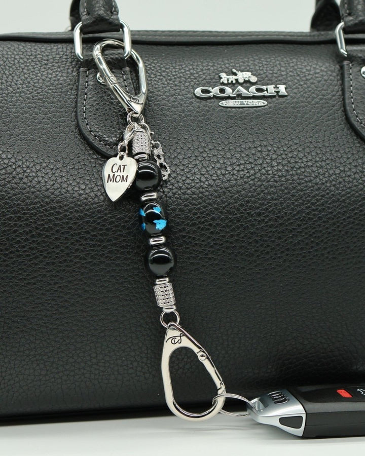 LD Keyfinder Whisker Dreams-Mini featuring black obsidian beads, blue foil cat glass, and Cat Mom charm on a handbag