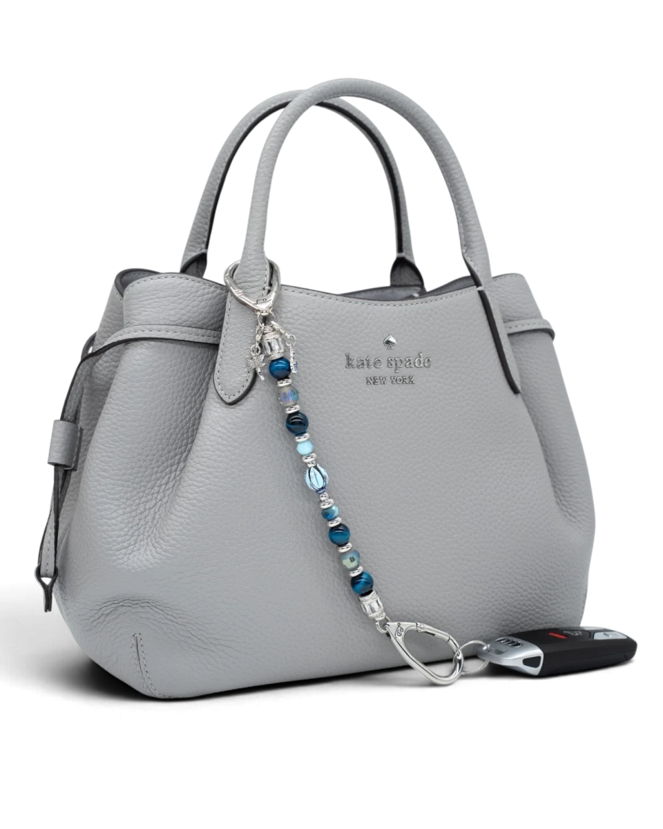 LD Keyfinder Whispering Garden beaded keychain with blue glass tulip, tiger eye, and charms attached to a grey handbag